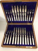 A set of twelve fruit knives and forks with mother of pearl handles and silver collars, the