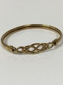 A 9ct gold Celtic knot bangle with clip fastening to top (6.5cm x 5cm) (7.74g)