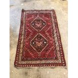 Persian design red ground rug, with double lozenge medallion within geometric border 83cm x 139cm