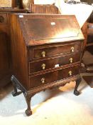 A Georgian style mahogany bureau, the fall front over a fitted interior, above three drawers, raised