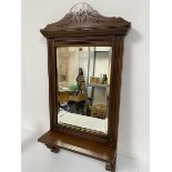 An Edwardian walnut shaving mirror with arched carved surmount and bevelled glass plate, with open