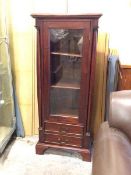 A Georgian inspired mahogany cabinet, with glazed door enclosing shelves and flanked by corinthian