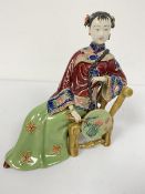 A Chinese pottery seated figure of a Young Girl holding a Fan, decorated with polychrome enamels,