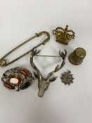 A white metal stag's head brooch, a white metal hardstone brooch (a/f), a cap badge, a white metal