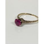 A yellow metal ring mounted solitaire synthetic circular cut ruby mounted in white metal claw