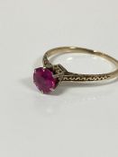 A yellow metal ring mounted solitaire synthetic circular cut ruby mounted in white metal claw