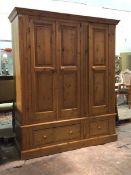 A Modern polished pine triple wardrobe, the interior fitted with hanging rails above two drawers