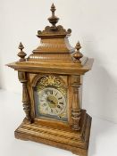 An Edwardian walnut mantel clock with pedimented top with three finials and silvered dial with roman