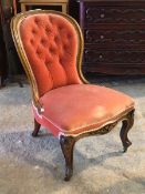 A Victorian mahogany spoon back bedroom chair, with buttoned upholstery, raised on floral carved