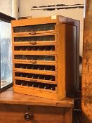 A 1940's oak table top collectors cabinet, with seven glazed drawers with interior partitions,