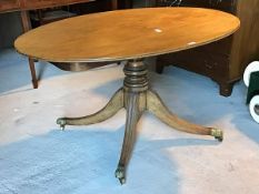 A Regency mahogany tilt top breakfast table, the oval top with reeded edge over turned column and