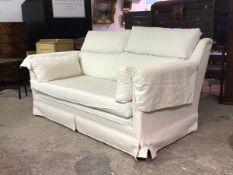 A contemporary two seat sofa, upholstered in a natural linen fabric with squab and scatter cushions,