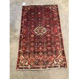Persian design red ground rug with lozenge medallion amongst flowerheads enclosed by border, 144cm x