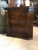 An oak wall hanging corner cupboard of 18th century design with dentil cornice and panelled cupboard