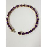 A 14ct gold tennis style link bracelet mounted twenty four oval cut amethysts with twin diamond