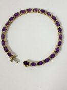 A 14ct gold tennis style link bracelet mounted twenty four oval cut amethysts with twin diamond