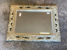 A traditional wall hanging bevelled mirror within a pierced floral carved frame, 56cm x 72cm