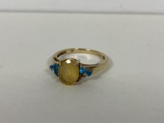 A 9ct gold ring with central oval cut citrine flanked by blue stones, one lacking (O) (2.16g)