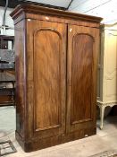 A Victorian walnut double wardrobe, the projecting cornice over two panelled doors enclosing an