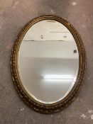 An oval Edwardian wall mirror, the bevelled glass within a foliate designed gilt frame, some
