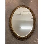 An oval Edwardian wall mirror, the bevelled glass within a foliate designed gilt frame, some