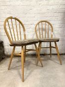 Ercol - A pair of blonde elm and beech dining chairs, with hoop and spindle back over saddle seat,