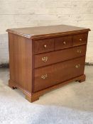 A Younger Furniture cherry wood chest, fitted with three short and two long drawers, raised on