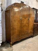 A Queen Anne style figured walnut triple wardrobe, the undulating top over two doors enclosing