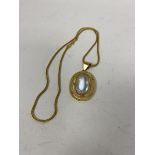 A moonstone cabouchon within a 9ct gold pendant, marked CM & Co. on a yellow metal chain (21cm) (5.