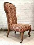 A Victorian rosewood nursing chair, the spoon back and seat upholstered in a cream ground cotton