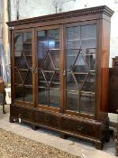 A George III style mahogany bookcase, with dentil cornice over three astragal glazed doors enclosing