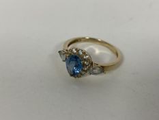 A 9ct gold ring set central pear cut blue stone surrounded by pale blue stones also to shoulders (P)