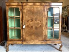 An early 20th century Queen Anne style figured walnut break front display cabinet, the top with