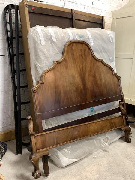 A 20th century mahogany 5' double bed, the arched headboard on castors and scrolled footboard on