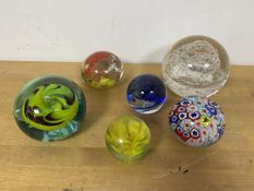 A collection of six glass paperweights, the largest with bubble spiral design with Selkirk Glass