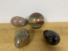 A group of three polished stone eggs, and a polished stone sphere (d.7cm)