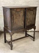 An 18th century style oak side cabinet, early 20th century, geometric panelled doors enclosing three