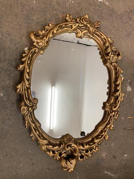 A modern wall mirror, the oval glass within a rococo style gilt composition frame (67cm x 50cm)