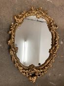 A modern wall mirror, the oval glass within a rococo style gilt composition frame (67cm x 50cm)