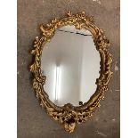 A modern wall mirror, the oval glass within a rococo style gilt composition frame (67cm x 50cm)