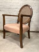 An early 20th century walnut bedroom open armchair, the oval back with cane panel over upholstered