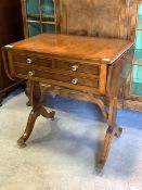 A Regency style cross banded yew wood sofa table, fitted with three drawers, raised on four