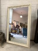 A Large cream painted wall hanging mirror, with floral moulded frame enclosing bevelled mirror 115cm