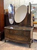 A 20th century figured walnut bowfront dressing chest, the top with triptych swing mirrors over