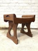 A 20th century stained teak stool, with concave top over scalloped apron, raised on pierced panel