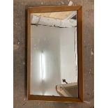 A mid century wall mirror, the glass within an angled trapezoid shaped teak frame (43cm x 80cm)