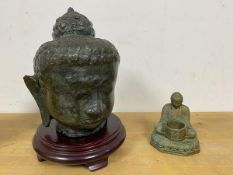 A South East Asian bust of a Deity, hollow metal, on stand (with stand: 23cm) and a Seated brass