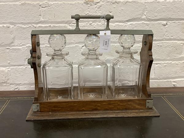 A Late Victorian/Edwardian oak tantalus, with three cut crystal square decanters, H32cm, W43cm,