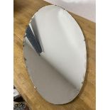 A modern oval mirror with bevelled wedges to edge (76cm x 38cm)
