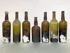 A group of seven 19th century armorial wine bottles, mostly green, each with the same moulded